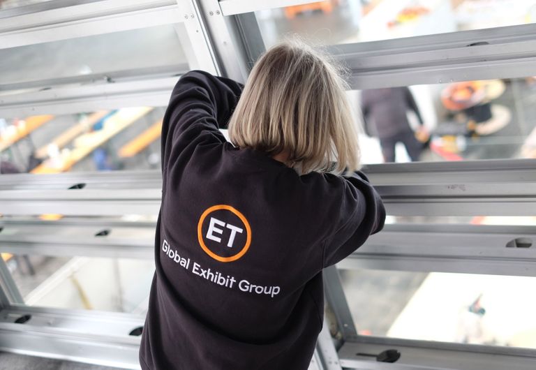 Mitarbeiterin von ET Global Exhibit Group bei der Arbeit mit besticktem Sweatshirt