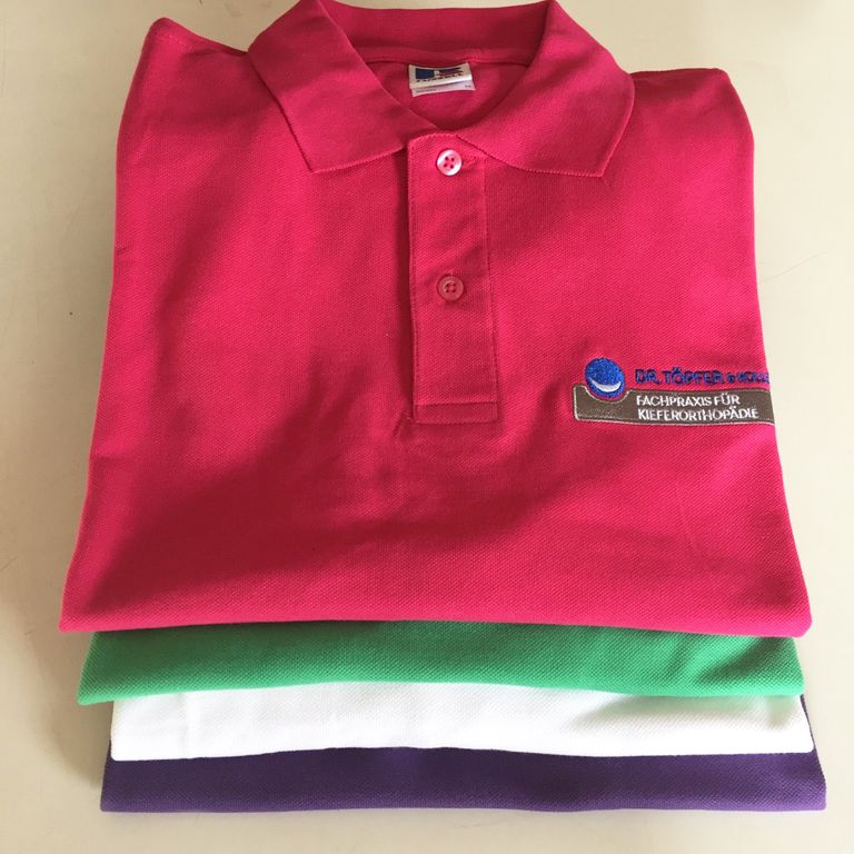 Ein Stapel mit bestickten Poloshirts - Arbeitskleidung für 'Dr. Töpfer & Kollegen Fachpraxis für Kieferorthopädie Hanau'