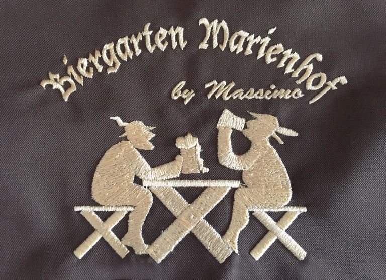 Detailaufnahme der Logo-Stickerei des Biergarten Marienhof by Massimo